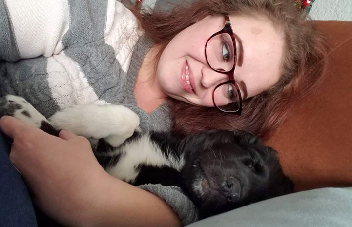 Woman lying down and snuggling with Reilly the puppy