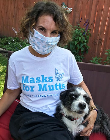 Sarah Pai wearing a mask and a Masks for Mutts T-shirt sitting next to a dog