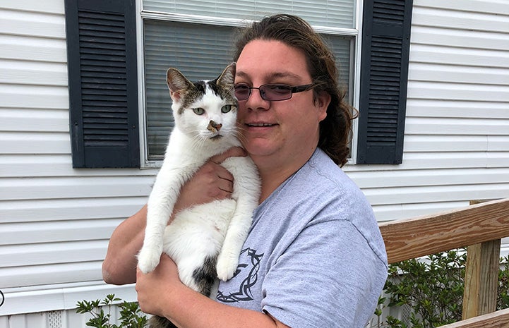 Smiling woman holding a tabby and white cat