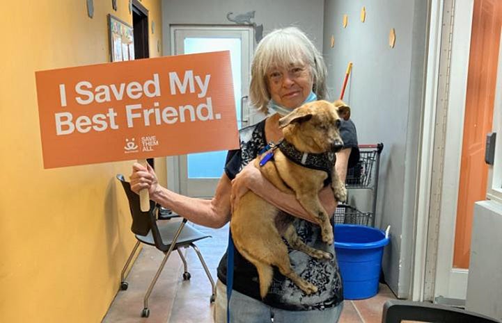 Lorraine adopting Minx the dog and holding a sign that says, I Save My Best Friend