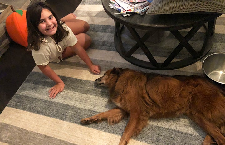 Young girl lying on the floor next to Tate the dog