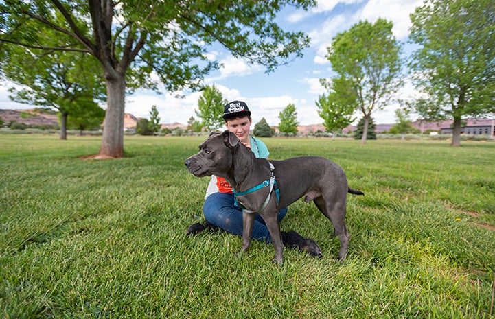 Chunk the dog standing next to Gherri, who is sitting in the grass