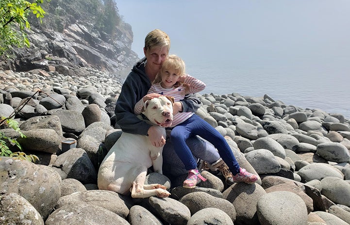 Doc the dog on a rocky beach with a woman and child