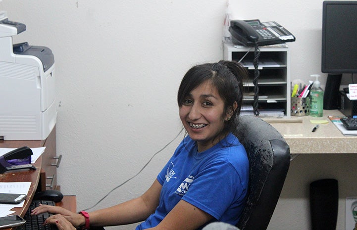 Yessy Banda sitting at a desk at Palm Valley Animal Center (PVAC)