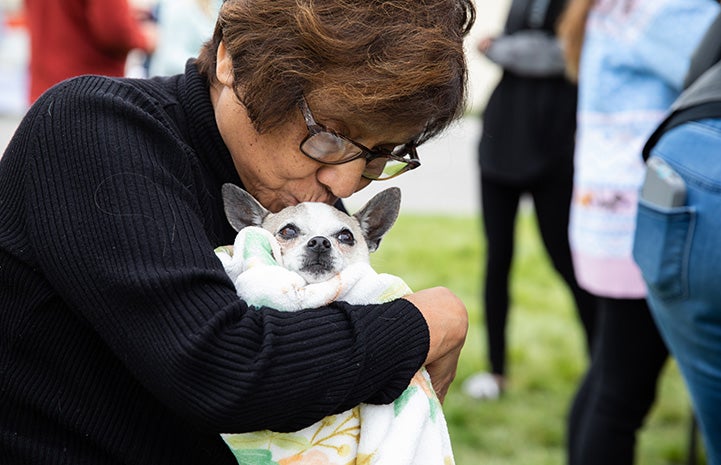 Woman kissing and hugging a small dog at the NKUT Super Adoption event