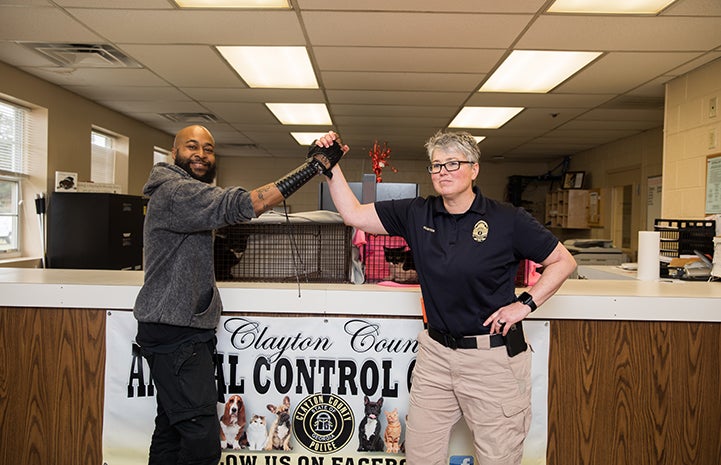 Sterling “Trap King” Davis holding hands up with a woman animal control officer