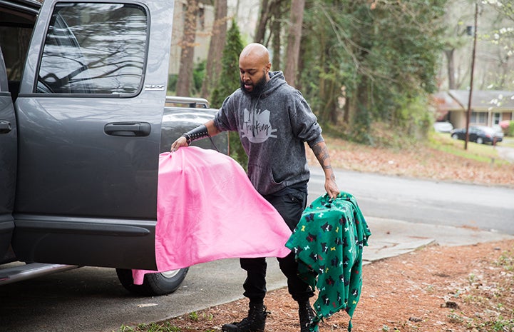 Sterling “Trap King” Davis holding two covered humane traps to a van