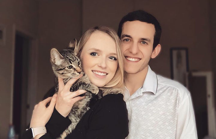 Smiling young couple holding Lincoln the tabby cat
