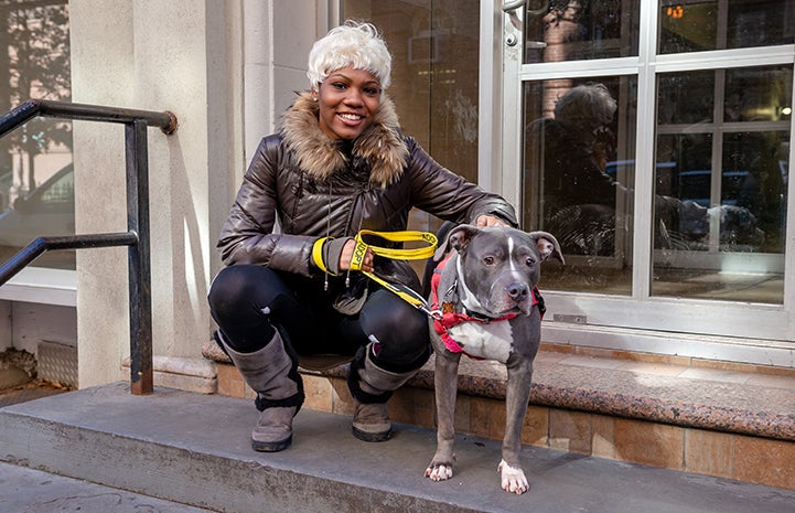 Woman on some steps next to the gray and white pit bull terrier she'd just adopted