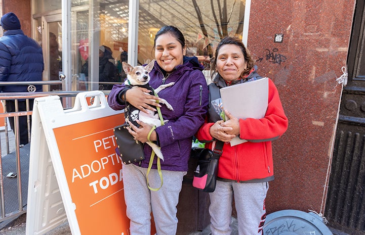 Two women holding a small dog at a New York Valentine's Day adoption event