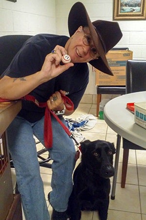 Veteran Sue Wright holding a bingo ball, next to her service dog Lady Diana