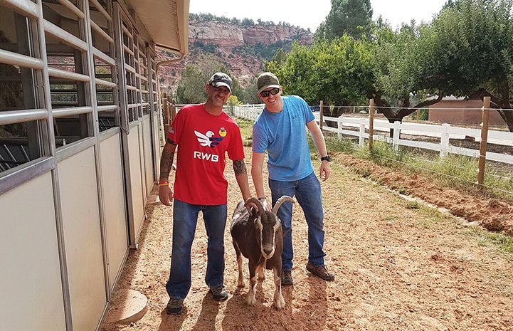 Rob and Josh from Team RWB take a break from volunteering to make friends with a goat