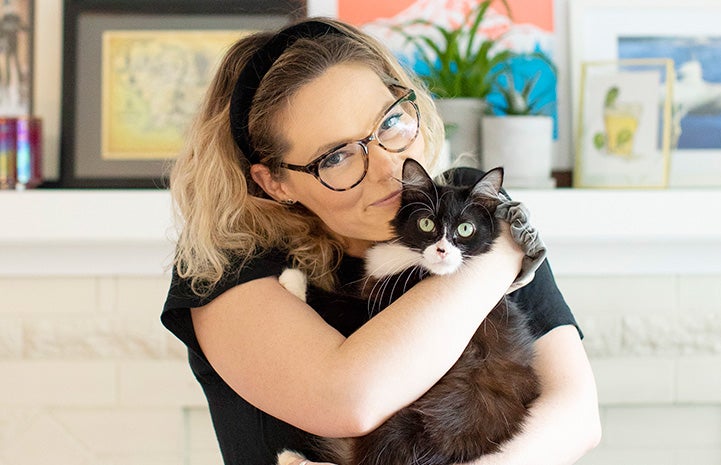 Woman hugging black and white cat she's adopting from Motley Zoo Animal Rescue