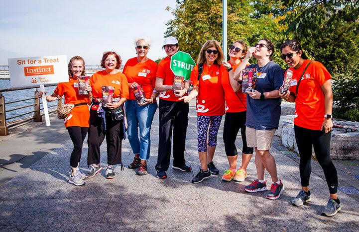 Group of volunteers wearing orange T-shirts working a treat station during a Strut Your Mutt event
