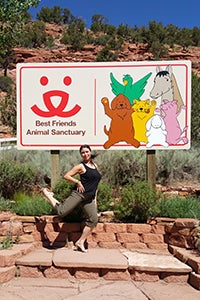 Volunteer Chelsea Eng in front of the Best Friends sign by the Welcome Center