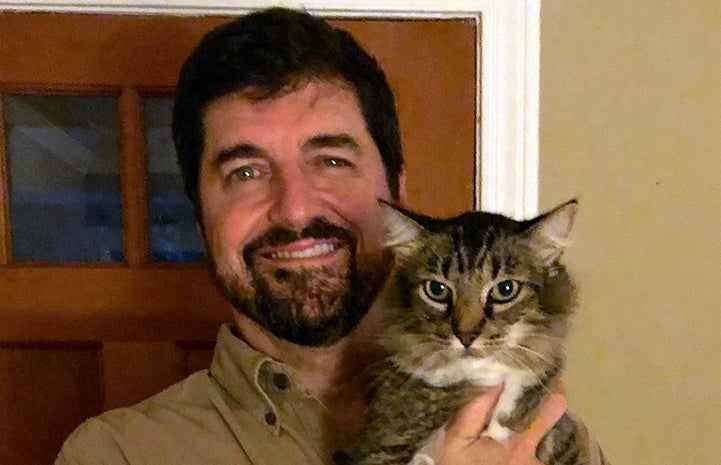 Volunteer Daniel Pruitt holding a brown tabby cat