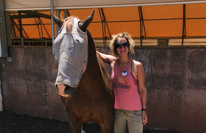 Jennifer Wesely next to a horse wearing a fly mask at Horse Haven