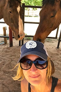 Jennifer Wesely volunteering at Horse Haven with two horses behind her