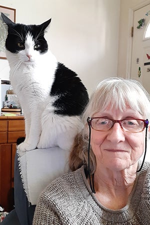 Volunteer Judy Steiger sitting next to a black and white cat