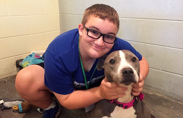 Julia in a kennel snuggling with a gray and white dog