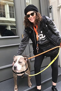 Volunteer Lauren Fishman walking a gray and white pit-bull-type dog