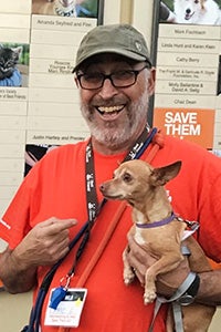 Volunteer David Glazer smiling and holding a Chihuahua mix dog