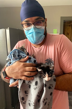 Volunteer Ramandeep Singh masked and holding a kitten in a towel