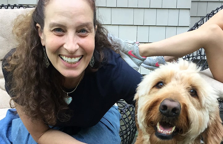 Volunteer Randi Schey posing next to a Labradoodle type dog