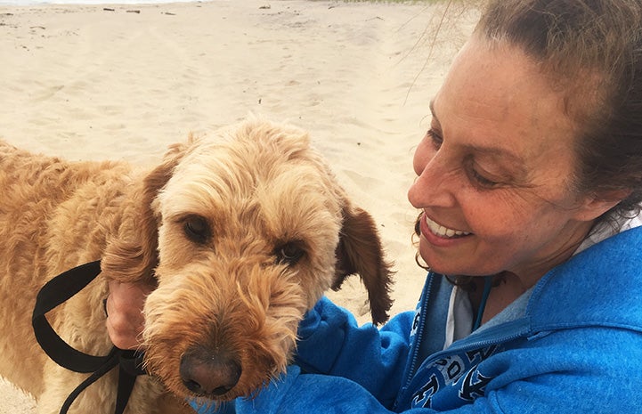 Volunteer Randi Schey at a beach with a Labradoodle type dog