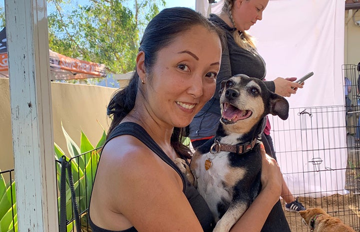 Volunteer Ranko Fukuda smiling and holding a terrier mix dog