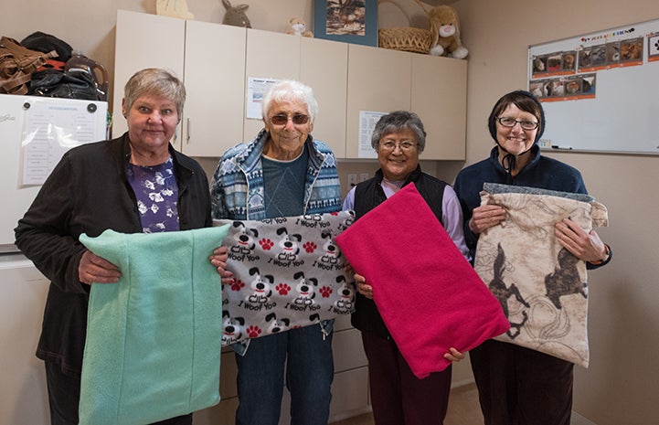 Group of four volunteers holding the blankets they'd sewed for Bunny House