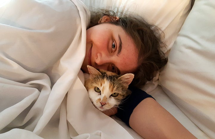 Volunteer Heather Slattery snuggled in bed with Eunice the cat on a sleepover