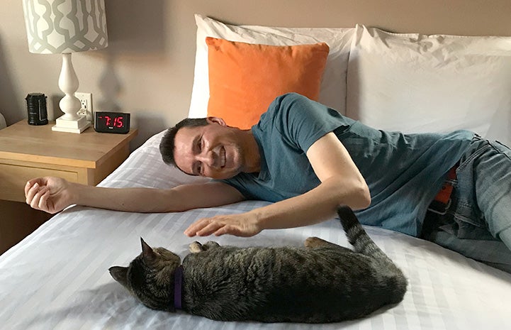 Mike on the bed with a cat for a sleepover