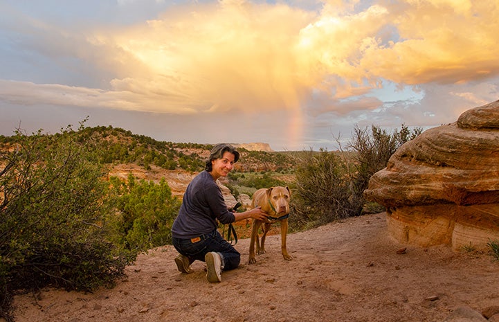 Andrea on an outing with a dog in Angel Canyon with sun and clouds behind them