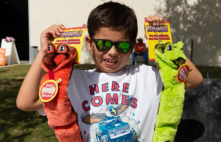 Young boy holding up two dog toys he's donating to an animal welfare organization