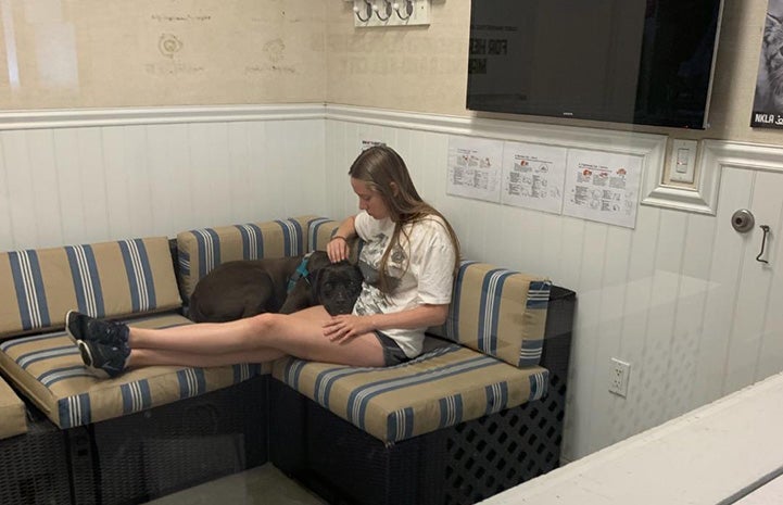 Woman lying on a couch at the NKLA Adoption Center with Gunner the dog on her lap