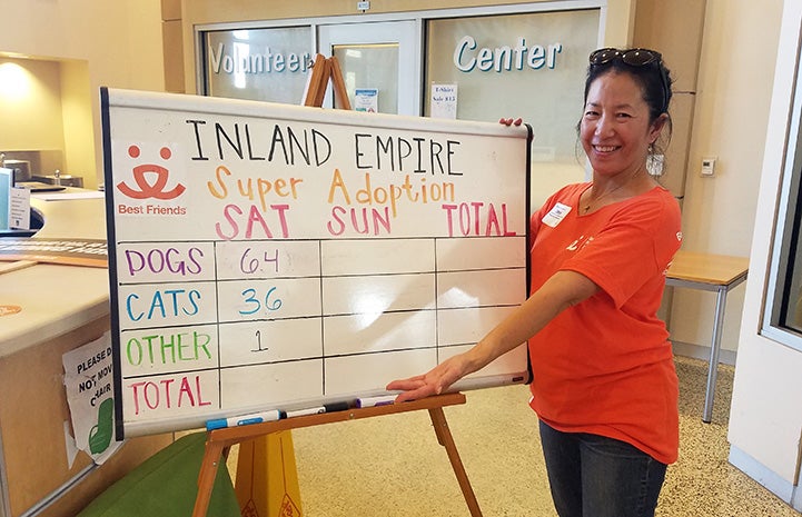 Volunteer Sophia Lim in front of a white board showing animals adopted at a Super Adoption event
