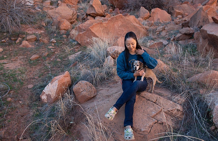 Ranko sitting on some red rocks holding Soba the dog