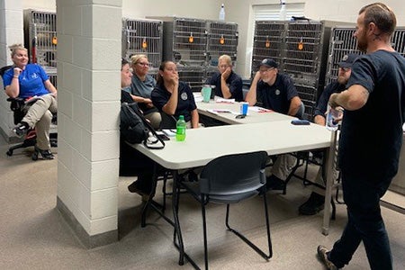 Group of people in a meeting with stainless steel kennels behind them