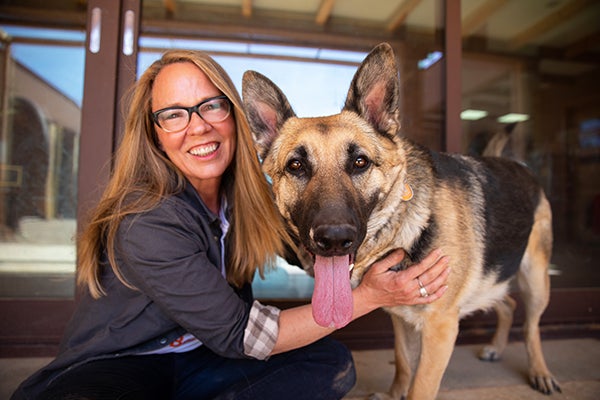 Julie Castle with her hand touching her German shepherd dog Sunny