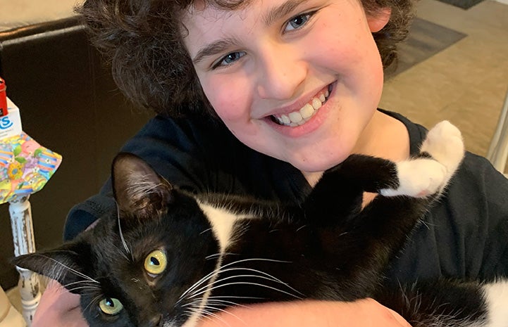 Lucas Uhrich cradling a black and white cat