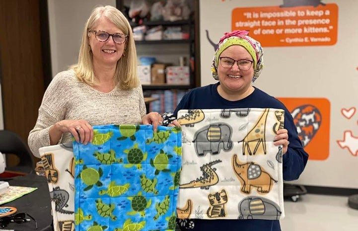 Volunteers Maggie Schroeder and April Bowerman holding mats for cats they had sewn