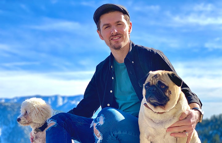 Volunteer Nathan Shaw with two dogs and a blue sky behind him