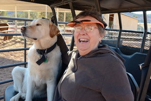 Sandy Batalden riding in a golf cart with a dog at Best Friends Animal Sanctuary