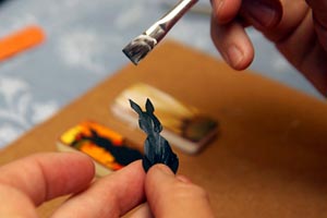 Woman creating and painting an upcycle rabbit necklace