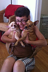 Woman snuggling two small tan dogs