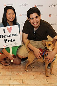 Couple with their adopted dog. Woman is holding a sign that says "I Love Rescue Pets."