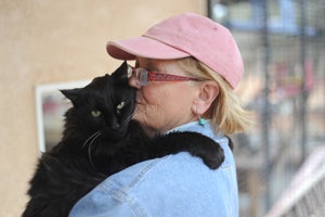 Patrick the black cat snuggling with caregiver Robin
