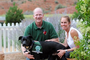 Therapy dog, a beautiful black Lab, with his adoptive mom and dad