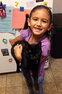 Little girl holding her adopted black cat